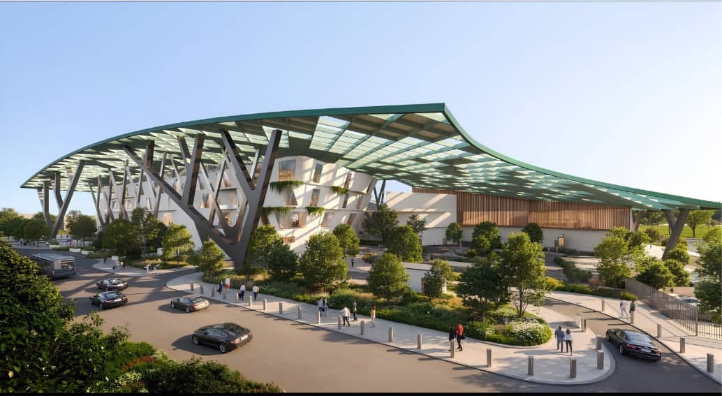 BENOY concept design render of the EAN Aeroplex airside campus at dusk, showing the hangar frontage lit from within, business jets and helicopters on the apron and an Airbus A320neo on the taxiway