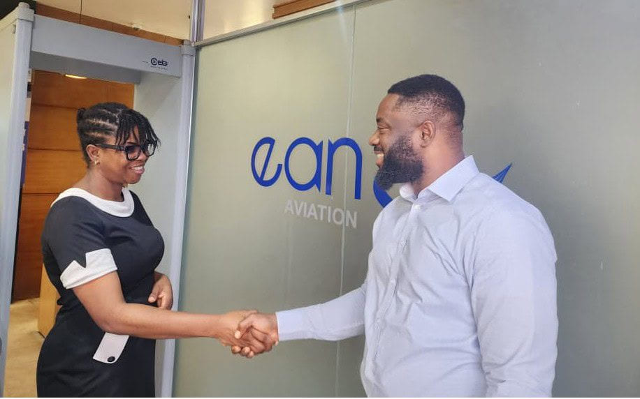 Two people shaking hands at the entrance to EAN Aviation’s office, beside the branded glass partition.