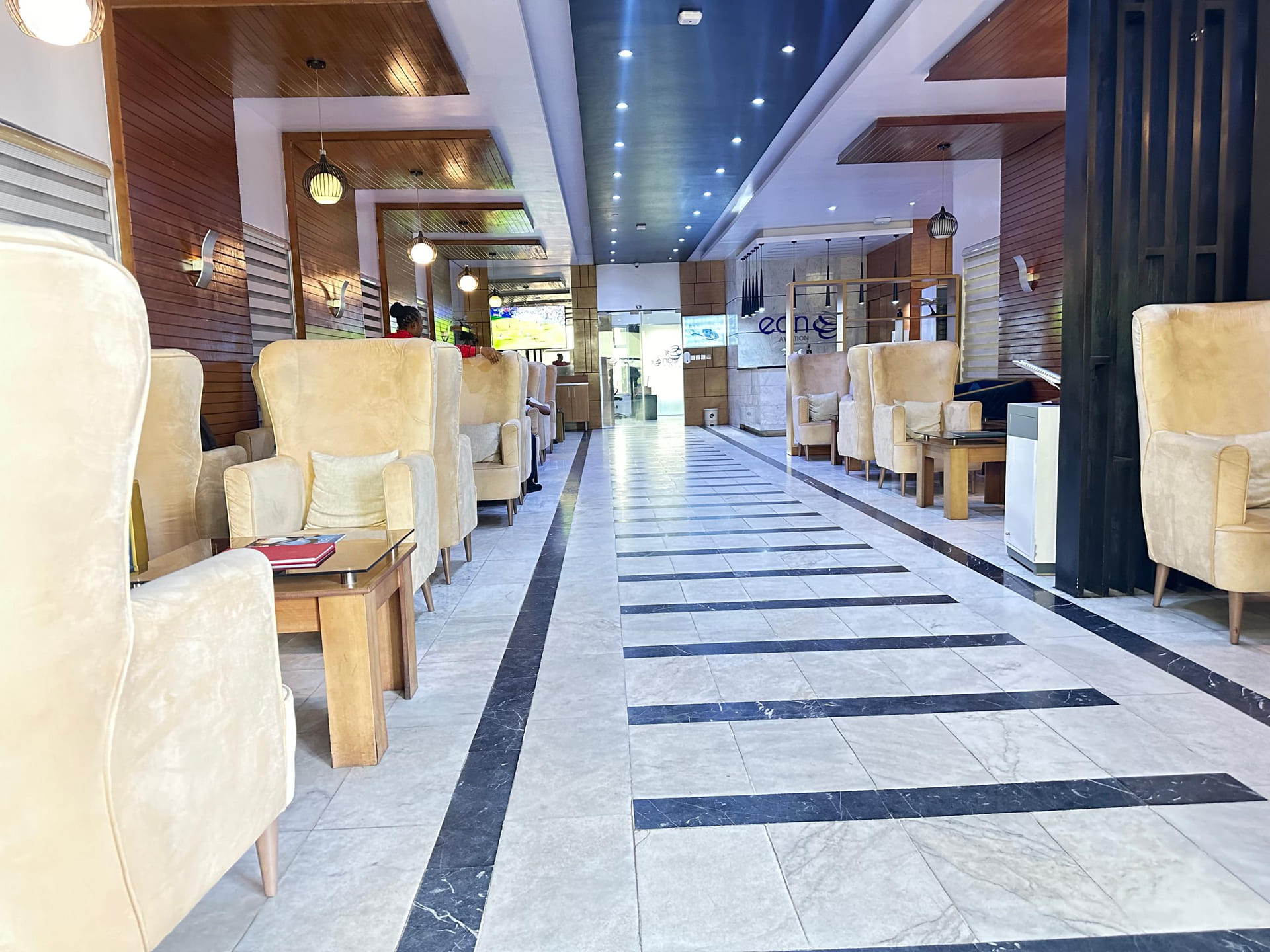 EAN Aviation’s VIP lounge, lined with cream wing-back armchairs along a marble floor leading to the branded reception.