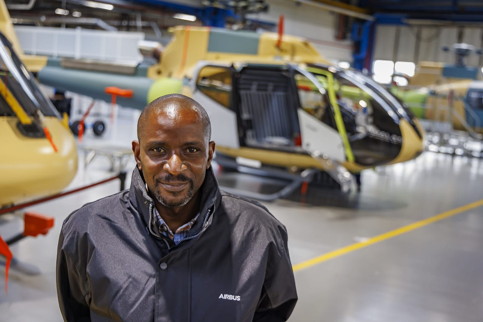 Tayo Aiyetan photographed in an Airbus jacket inside a helicopter hangar.
